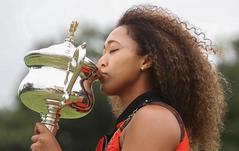 Japan's Naomi Osaka kisses the Daphne Akhurst Memorial Cup during a photo shoot at Government House the day after defeating United States Jennifer Brady in the women's singles final at the Australian Open tennis championship in Melbourne, Australia, Sunday, Feb. 21, 2021.(AP Photo/Hamish Blair)