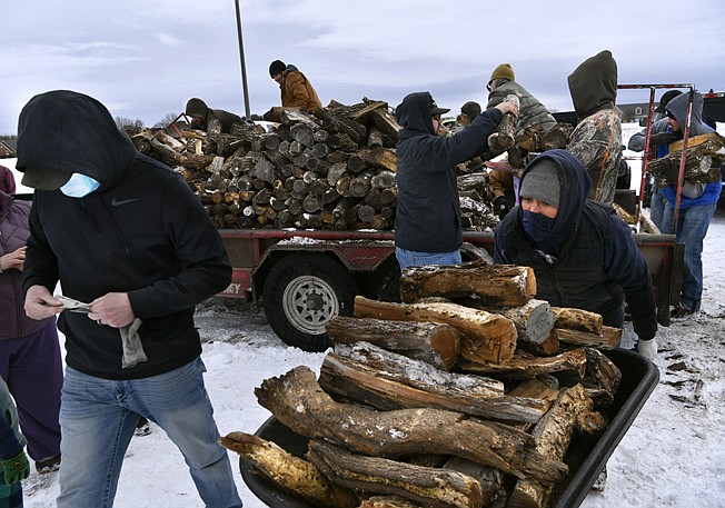 A wheelbarrow full of wood is pushed to a waiting pickup Feb. 16 in south Abilene, Texas. Trucks from an Albany, Texas, tree service 30 miles away hauled more than a dozen cords of seasoned wood on several trailers, selling them in the parking lot of the former furniture store on Buffalo Gap Road. 