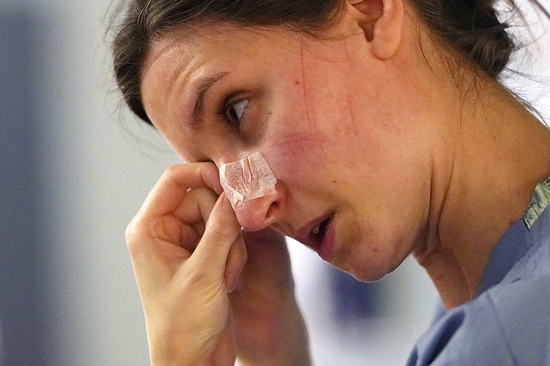 FILE - In this Jan. 26, 2021, file photo, with indentations from a N-95 mask marking her face, registered nurse Lilyrose Fox peels protective tape from her nose after working in patients rooms in the COVID acute care unit at UW Medical Center-Montlake, in Seattle. The U.S. death toll from COVID-19 has almost topped 500,000 — a number so staggering that a top health researchers says it is hard to imagine an American who hasn't lost a relative or doesn't know someone who died. (AP Photo/Elaine Thompson, File)
