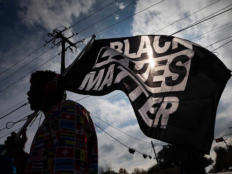 In this Dec. 12, 2020, file photo, MD Crawford carries a Black Lives Matter flag before a march in La Marque, Texas to protest the shooting of Joshua Feast, 22, by a La Marque police officer. A financial snapshot shared exclusively with The Associated Press shows the Black Lives Matter Global Network Foundation took in just over $90 million last year. (Stuart Villanueva /The Galveston County Daily News via AP, File)