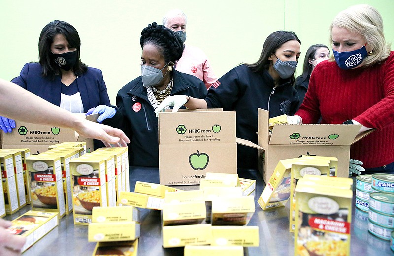 Texas congresswoman Penny Morales Shaw, from left, joins U.S. Representatives Sheila Jackson Lee, Alexandria Ocasio-Cortez and Sylvia Garcia,  as they fill boxes at the Houston Food Bank on Saturday, Feb. 20, 2021.   President Joe Biden declared a major disaster in Texas on Friday, directing federal agencies to help in the recovery.  (Elizabeth Conley/Houston Chronicle via AP)