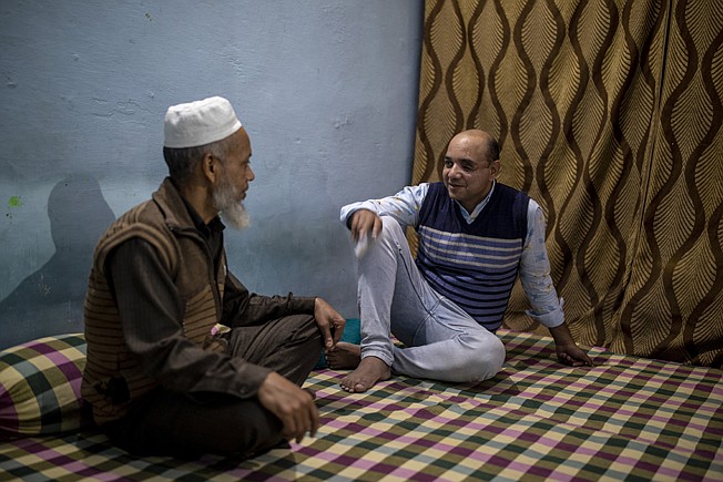 Muhammad Nasir Khan, right, who was shot by a Hindu mob during the February 2020 communal riots, speaks to his father Abdul Jaleel inside his home  in North Ghonda, one of the worst riot affected neighborhood, in New Delhi, India, Friday, Feb. 19, 2021. As the first anniversary of bloody communal riots that convulsed the Indian capital approaches, Muslim victims are still shaken and struggling to make sense of their struggle to seek justice. (AP Photo/Altaf Qadri)