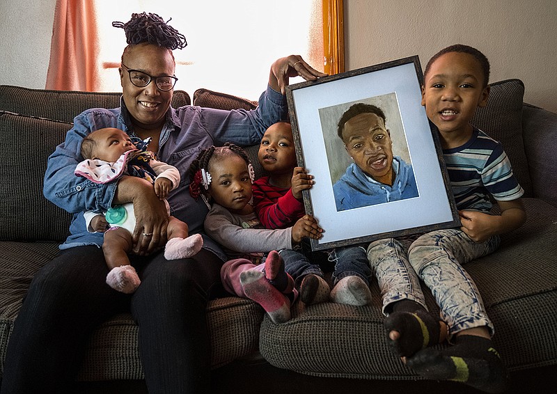 Skyla Pawnell, left, and her grandchildren, from left, Lyric Jenkins, 2 months-old, Ka'marri Dorris, 2, Tristan Jenkins, 3, and Eric Jenkins, 6, pose for a portrait at Pawnell's home in Centreville on Friday, Feb. 19, 2021 with a drawing of their uncle and Pawnell's son, Aaron Prayer, who was killed in East St. Louis at the age of 21 in 2018. Pawnell was gifted a portrait of him from Faces Not Forgotten, a St. Louis non-profit that paint portraits of young people who have been killed in homicides nationwide. (Cheyenne Boone/St. Louis Post-Dispatch/TNS)