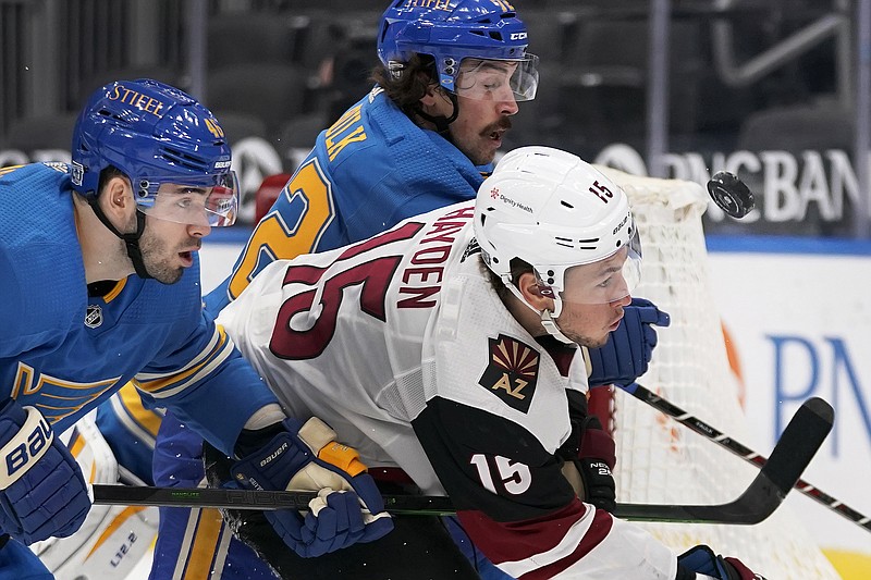 Blues teammates Jake Walman (left) and Justin Faulk chase after a loose pick with John Hauden of the Coyotes during a game earlier this month in St, Louis.