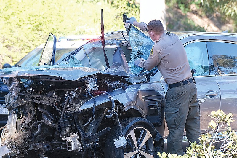 A law enforcement officer looks over a damaged vehicle Tuesday following a rollover accident involving Tiger Woods in the Rancho Palos Verdes suburb of Los Angeles.