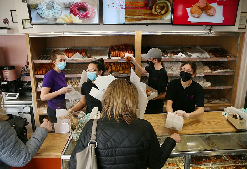 Spunky Dunkers workers from left, Maggie O'Brien, Michelle Hanrahan, Brenday Rolloff and Ilianna Giannakouras hustle to fill donut orders at Spunky Dunkers on Feb. 21, 2021, in Palatine. People from all over the area have been lining up outside to show support to the struggling business.   (Stacey Wescott / Chicago Tribune/TNS)