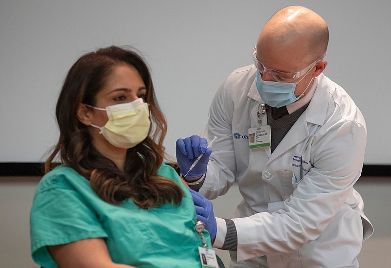 OhioHealth Director of Infectious Diseases Joseph Gastaldo gives Dr. Simrit Bhullar, a pulmonary and critical care physician, a COVID-19 vaccination at OhioHealth Riverside Methodist Hospital in Columbus on Wednesday, Dec. 16, 2020. (Adam Cairns/Columbus Dispatch/TNS)