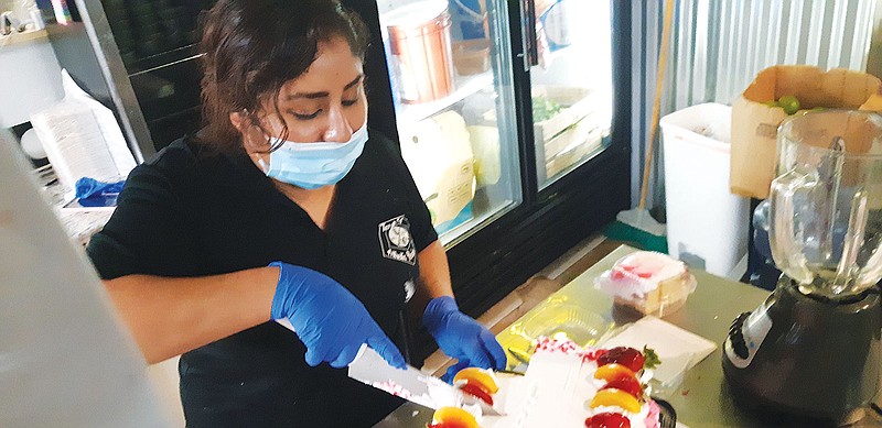 Adrianna Herrera carves one of the cakes Taco Trip is known for, calling it their secret "Tres Leches" recipe. Taco Trip started out as a food truck business. They have now settled in a permanent building on New Boston Road.