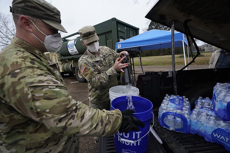Mississippi Army National Guard Sgt. Chase Toussaint, right, and Staff Sgt. Matthew Riley, both with the Maneuver Area Training Equipment Site of Camp Shelby, fill 5-gallon water drums with non-potable water, Monday, March 1, 2021, at a Jackson, Miss., water distribution site on the New Mount Zion Missionary Baptist Church parking lot. Water for flushing toilets was being distributed at seven sites in Mississippi's capital city, more than 10 days after winter storms wreaked havoc on the city's water system because the system is still struggling to maintain consistent water pressure, authorities said. (AP Photo/Rogelio V. Solis)