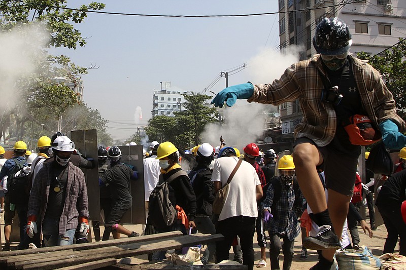 Protesters are dispersed as riot police fired tear gas behind a makeshift barricade in Yangon, Myanmar, Sunday, March 7, 2021. The escalation of violence in Myanmar as authorities crack down on protests against the Feb. 1 coup is raising pressure for more sanctions against the junta, even as countries struggle over how to best sway military leaders inured to global condemnation. (AP Photo)