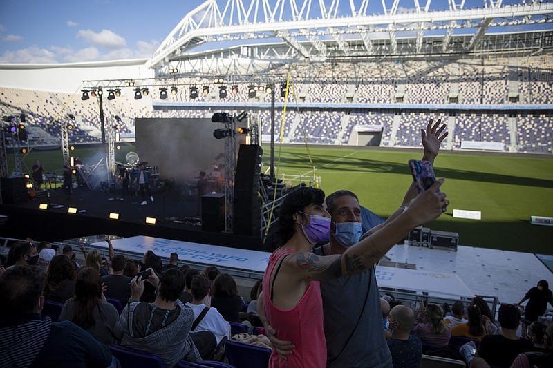 Audience members wearing protective face masks take a selfie during a performance of Israeli musician Ivri Lider, where all guests were required to show "green passport" proof of receiving a COVID-19 vaccination or full recovery from the virus at a soccer stadium in Tel Aviv, Friday, March. 5, 2021. (AP Photo/Oded Balilty)