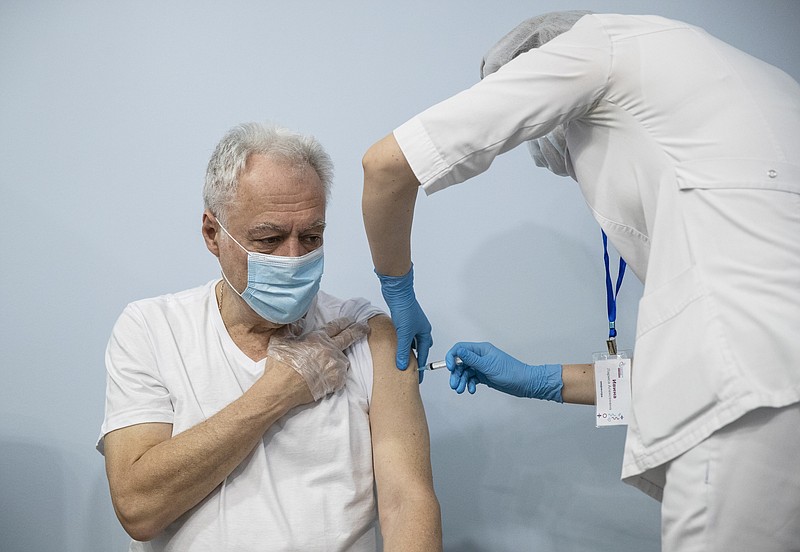 FILE - In this Jan. 20, 2021, file photo, a Russian medical worker, right, administers a shot of Russia's Sputnik V coronavirus vaccine to a patient in a vaccination center in Moscow, Russia. Russia’s boast in August that it was the first country to authorize a coronavirus vaccine led to skepticism because of its insufficient testing on only a few dozen people. Now, with demand growing for the Sputnik V, experts are raising questions again, this time over whether Moscow can keep up with all the orders from countries that want it. (AP Photo/Pavel Golovkin, File)