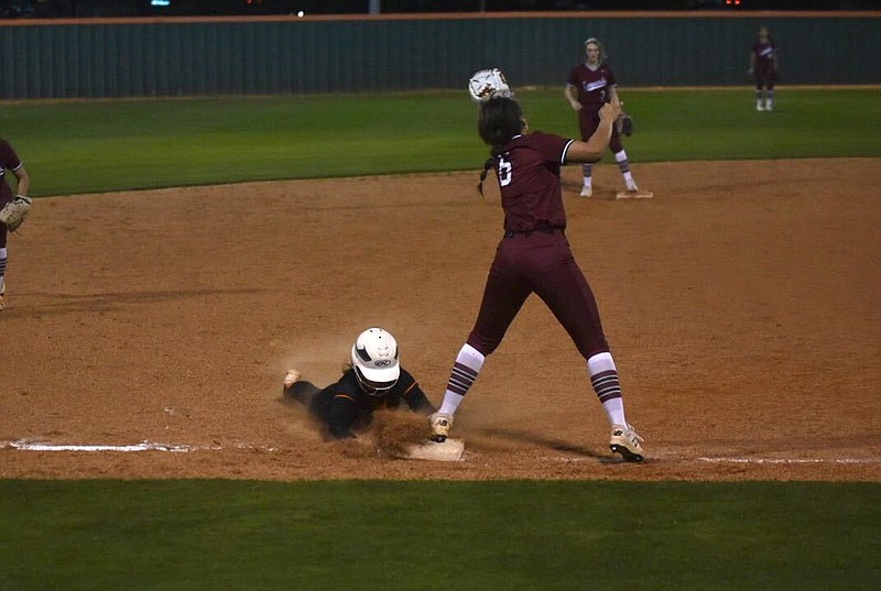 Texas High player Mollie Johnson slides into third base just before Liberty-Eylau player Hannah Burden catches the ball being passed to her during their game Tuesday night at Texas High.

