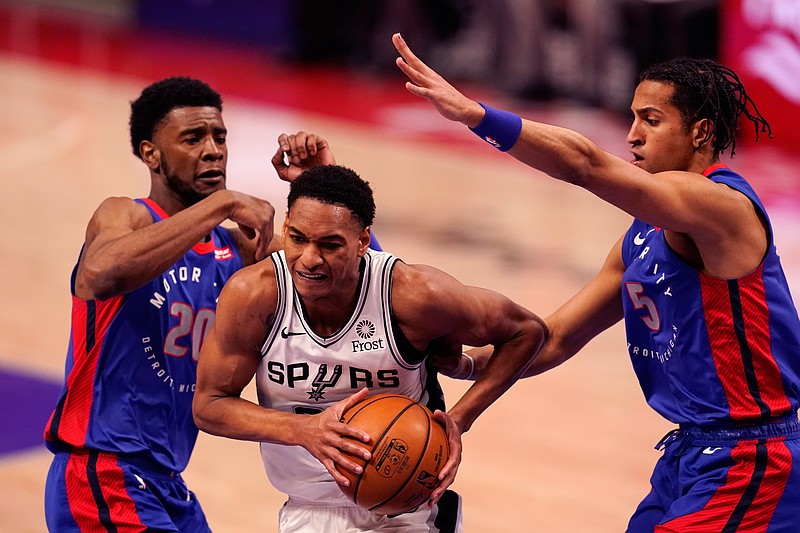 San Antonio Spurs guard Devin Vassell (24) drives between Detroit Pistons guard Josh Jackson (20) and guard Frank Jackson (5) during the second half of an NBA basketball game, Monday, March 15, 2021, in Detroit. (AP Photo/Carlos Osorio)