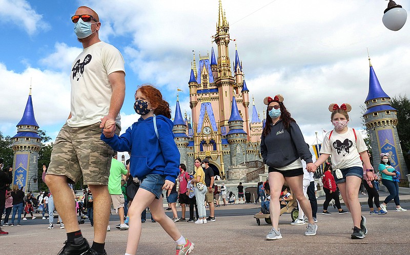 A masked family walks past Cinderella Castle in the Magic Kingdom, at Walt Disney World in Lake Buena Vista, Florida, on Dec. 21, 2020. (Joe Burbank/Orlando Sentinel/TNS)