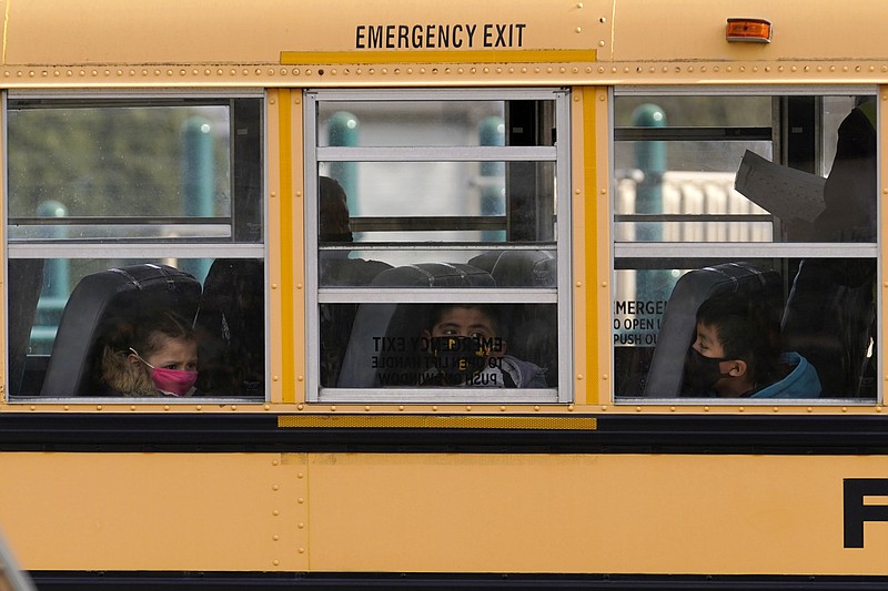 FILE - In this Thursday, Nov. 19, 2020, file photo, elementary school students sit on board a school bus after attending in-person classes at school in Wheeling, Ill. The latest federal relief package includes $81 billion that began flowing to states in late March 2021 with the goal of helping schools reopen quickly. The only problem is many of the school districts' current problems can't be solved by money. (AP Photo/Nam Y. Huh, File)