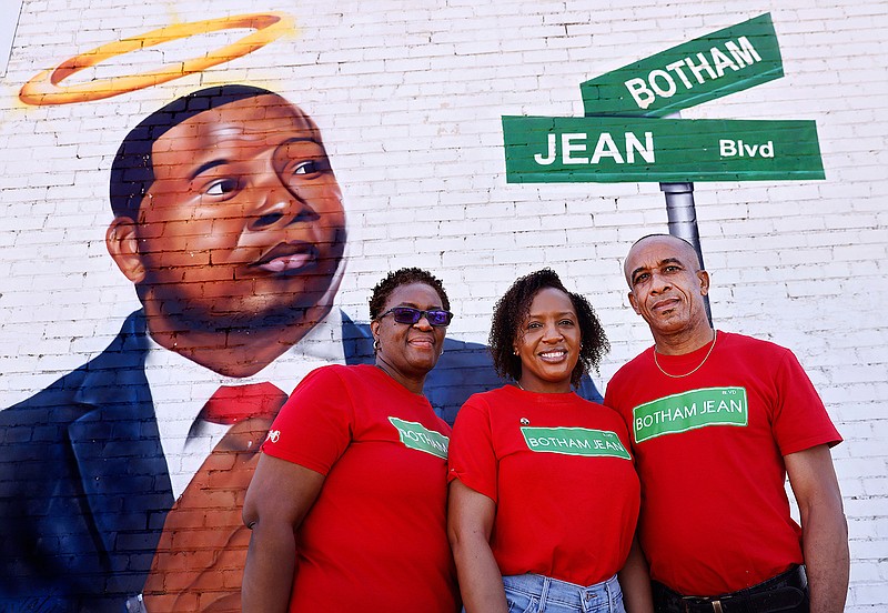 Allison Jean, her daughter Alissa Charles-Findley and husband Bertram Jean pose for a photo before a painted portrait of their slain son and brother, Botham Jean, on South Lamar at Cadiz St near downtown Dallas, Friday, March 26, 2020. Beforehand, the family held a news conference about the unveiling of Botham Jean Blvd this weekend. Jean was shot and killed in his apartment a few blocks away from this site by former Dallas Police Amber Guyger. Guyger was found guilty of murder by a 12-person jury in October of 2019. (Tom Fox/The Dallas Morning News/TNS)