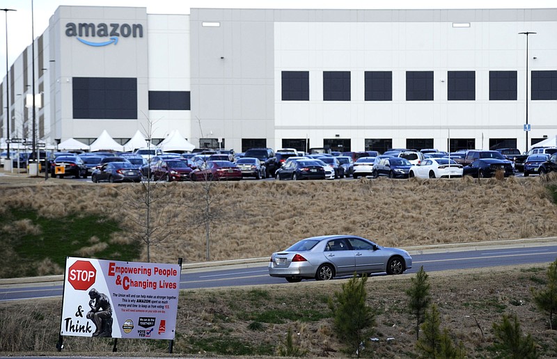 FILE- This Feb. 9, 2021 photo file photo,  a car enters an Amazon facility where labor is trying to organize workers in Bessemer, Ala.  Organizers are pushing for some 6,000 Amazon workers  to join the Retail, Wholesale and Department Store Union on the promise it will lead to better working conditions, better pay and more respect. Amazon is pushing back, arguing that it already offers more than twice the minimum wage in Alabama and workers get such benefits as health care, vision and dental insurance without paying union dues.  (AP Photo/Jay Reeves, File)