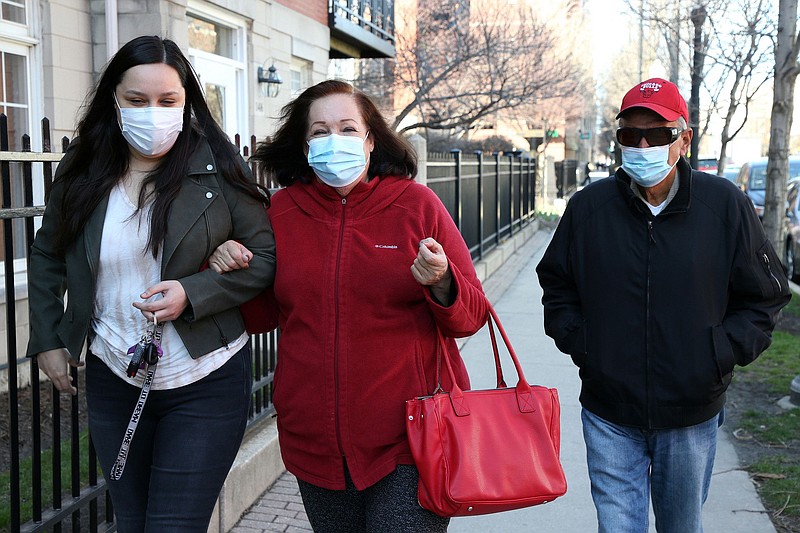 Elizabeth Oyarzun and her grandparents Irma Rodriguez and Jose Perez walk to the United Center vaccine site in Chicago on March 29, 2021.   (Terrence Antonio James / Chicago Tribune/TNS)