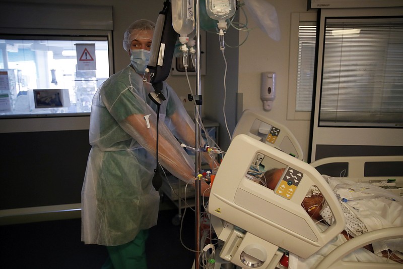 A medical worker moves a patient affected with the COVID-19 in the Amiens Picardie hospital Tuesday, March 30, 2021 in Amiens, 160 km (100 miles) north of Paris. France is now facing a deadly new surge of the virus that is overwhelming many hospitals, as critics accuse the government of ignoring warning signs and favoring political concerns over public health. (AP Photo/Francois Mori)