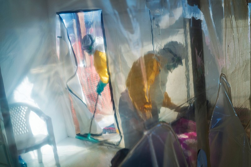 In this  July 13, 2019 file photo, health workers wearing protective suits tend to an Ebola victim kept in an isolation cube in Beni, Congo. According to a report published in the New England Journal of Medicine on Wednesday, March 31, 2021, an African man who developed Ebola despite receiving a vaccine recovered, but he suffered a relapse nearly six months later that led to 91 new cases before he died. The report adds to evidence that the deadly virus can lurk in the body long after symptoms end, and that survivors need monitoring for their own welfare and to prevent spread. (AP Photo/Jerome Delay, File)