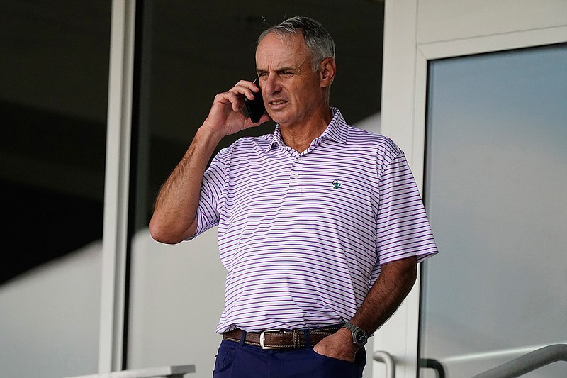 Major League Baseball commissioner Rob Manfred speaks on his phone as he watches a spring training baseball game between the Atlanta Braves and Boston Red Sox on Wednesday, March 10, 2021, in Fort Myers, Fla.. (AP Photo/John Bazemore)