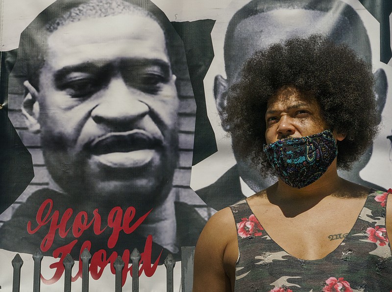 Actor Steven Thompson poses for a picture next to a poster of George Floyd in Los Angeles Friday, April 2, 2021. Thompson is choosing not to watch the televised trial of Derek Chauvin, the white police officer charged in the death of George Floyd, has provoked strong emotions among many Black men and women, all tinged with an underlying dread that it could yield yet another devastating disappointment, even though he feels there is a strong case against him. (AP Photo/Damian Dovarganes)