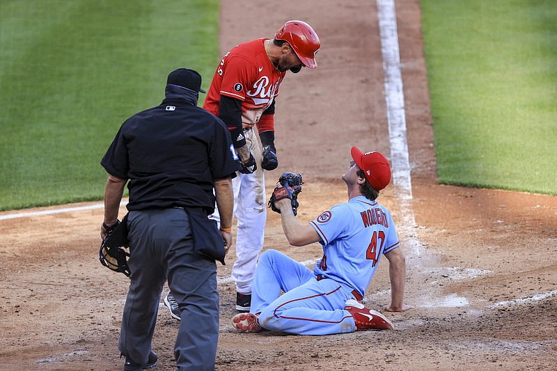 Nick Castellanos of the Reds reacts after scoring a run ahead of a tag by Cardinals pitcher Jake Woodford during the fourth inning of Saturday's game in Cincinnati.