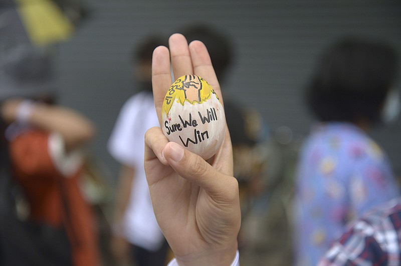 An anti-coup protester raises a decorated Easter egg along with the three-fingered symbol of resistance during a protest against the military coup on Easter Sunday, April 4, 2021, in Yangon, Myanmar. (AP Photo)