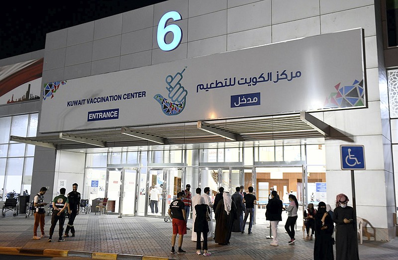 In this Friday, March 12, 2021 photo released by Kuwait News Agency, KUNA, people enter Kuwait Vaccination Centre to get the vaccine in Kuwait. In the tiny, oil-rich sheikhdom of Kuwait, the foreigners who power the country's economy, serve its society and make up 70% of its population are struggling to get COVID-19 vaccines. (KUNA via AP)