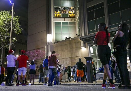 Onlookers watch from the street as inmates chant and throw things from broken windows at the St. Louis Justice Center, known as the city jail, on Sunday, April 4, 2021. (Colter Peterson/St. Louis Post-Dispatch via AP)