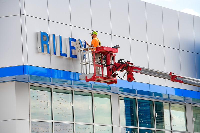 Julie Smith/News Tribune
Jared Goble spent a portion of his day Monday installing logo signage at Riley Chevrolet Buick GMC Cadillac on Christy Drive. Goble works for Columbia Sign Service and just one of many subcontractors working to finish up the dealership’s new building which replaces the old one that was heavily damaged in the May 2019 tornado.  Although the building looks much the same, some changes have been made including the location of the service entrance which is now on the south side of the building.