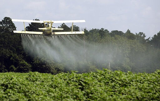 In this Aug. 4, 2009 file photo, a crop duster sprays a field in Alabama. A study published in the journal Science on Thursday, April 1, 2021 finds that farmers in the U.S. are using smaller amounts of better targeted pesticides, but these are harming pollinators, aquatic insects and some plants far more than decades ago. (AP Photo/Dave Martin, File)