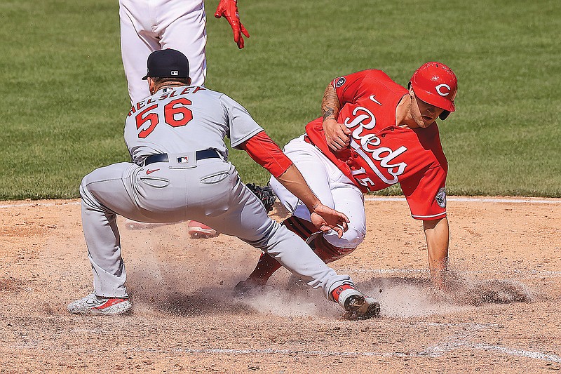 Nick Senzel of the Reds beats a tag at a plate from Ryan Hensley of the Cardinals during the sixth inning of Sunday's game in Cincinnati.