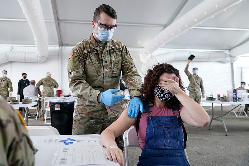 In this April 5, 2021, file photo, Leanne Montenegro, 21, covers her eyes as she doesn't like the sight of needles, while she receives the Pfizer COVID-19 vaccine at a FEMA vaccination center at Miami Dade College in Miami. Nearly half of new coronavirus infections nationwide are in just five states, including Florida — a situation that puts pressure on the federal government to consider changing how it distributes vaccines by sending more doses to hot spots.  (AP Photo/Lynne Sladky, File)