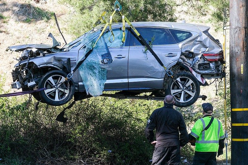 In this Feb. 23, 2021, file photo, a crane is used to lift a vehicle following a rollover accident involving golfer Tiger Woods, in the Rancho Palos Verdes suburb of Los Angeles. Authorities said Wednesday, April 7, Woods was speeding when he crashed leaving him seriously injured. (AP Photo/Ringo H.W. Chiu, File)