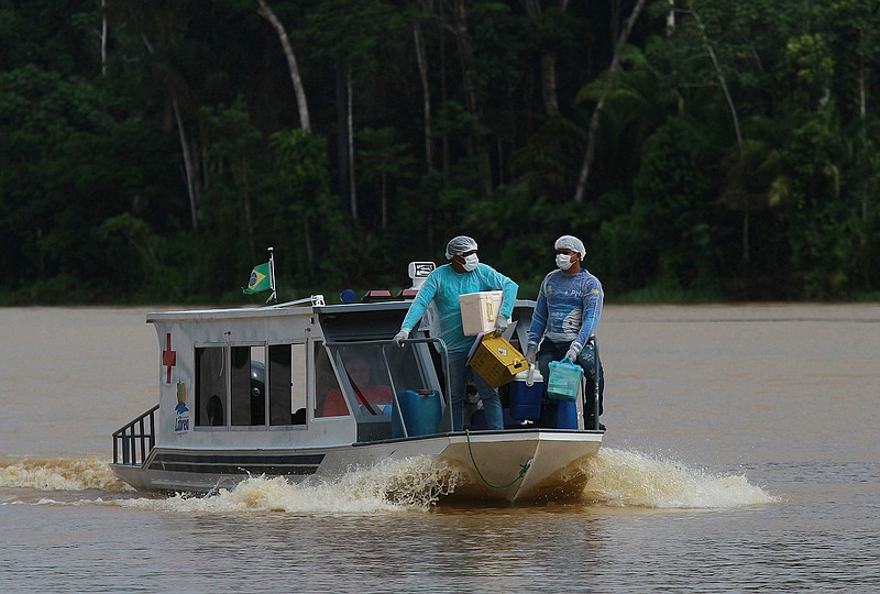 Healthcare workers Diego Feitosa Ferreira, 28, right, and Clemilton Lopes de Oliveira, 41, travel on a boat to the Santa Rosa community, Amazonas state, Brazil, Friday, Feb. 12, 2021, to vaccinate residents with the AstraZeneca COVID-19 vaccine. Getting the vaccine to the villages was important since most jungle communities have only basic medical facilities that aren't equipped to treat severe COVID-19 cases. (AP Photo/Edmar Barros)