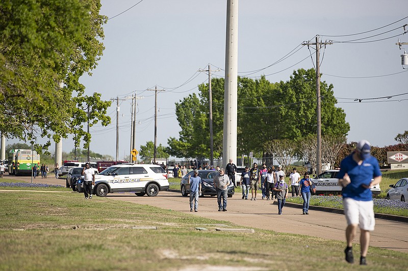 Police responded to a shooting at Kent Moore Cabinets on Thursday, April 8, 2021, in Bryan, Texas. One person was killed and several people were wounded Thursday in the wake of a shooting at a cabinet-making business in Bryan, Texas, authorities said, and a state trooper was later shot during a manhunt that resulted in the suspected shooter being taken into custody. (Cassie Stricker/College Station Eagle via AP)