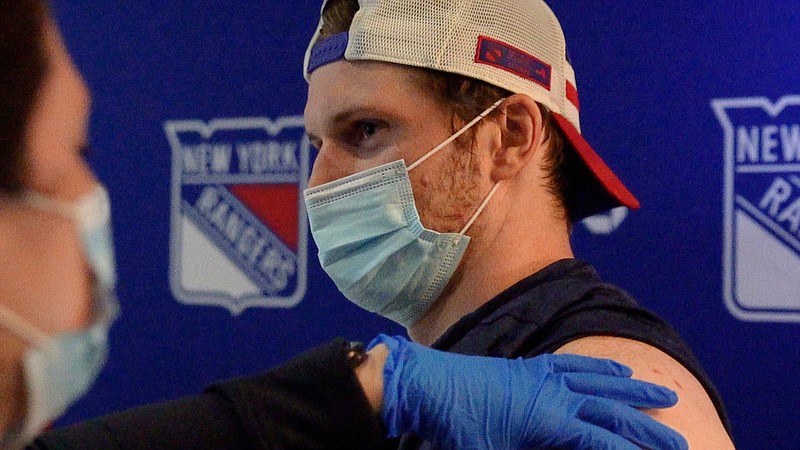 This photo provided by the New York Rangers shows New York Rangers NHL hockey defenseman Jacob Trouba receiving a dose of COVID-19 vaccine at Madison Square Garden in New York on Wednesday, April 7, 2021. The New York Rangers canceled practice so players, coaches and staff could get vaccinated against COVID-19, and Trouba was front and center to take his shot off the ice. (Nick Homler/New York Rangers via AP)