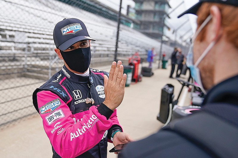 Helio Castroneves talks with a crew member during testing Thursday at the Indianapolis Motor Speedway in Indianapolis.