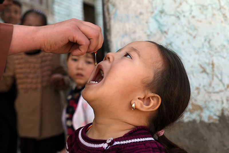 Shabana Maani, gives a polio vaccination to a child in the old part of Kabul, Afghanistan, Monday, March 29, 2021. Afghanistan is inoculating millions of children against polio after pandemic lockdowns stalled the effort to eradicate the crippling disease. But the recent killing of three vaccinators points to the dangers facing the campaign. (AP Photo/Rahmat Gul)