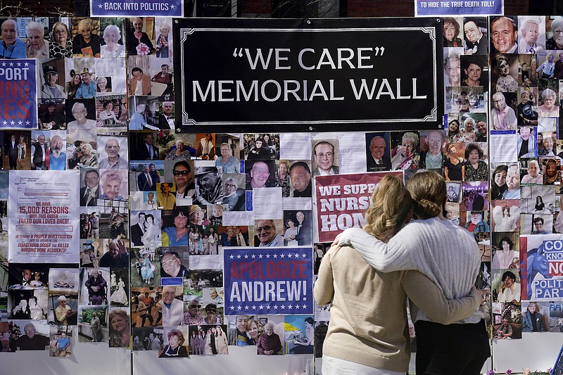 FILE - In this March 21, 2021 file photo, Theresa Sari, left, and her daughter Leila Ali look at a section of a memorial wall after a news conference in New York Sari's mother, Maria Sachse, was a nursing home resident and died from COVID-19. After a deadly year in New York’s nursing homes, state lawmakers have passed legislation that could potentially force facility owners to spend more on patient care.   (AP Photo/Seth Wenig)