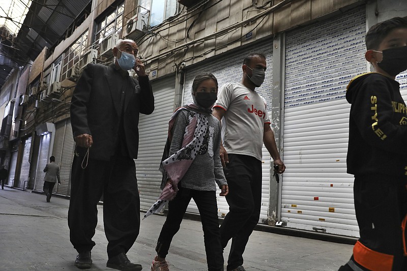 People walk through closed Tehran's Grand Bazaar, Iran, Saturday, April 10, 2021. Iran on Saturday imposed partial lockdown on businesses in major shopping centers as well as intercity travels through personal cars in major cities including capital Tehran as it struggles with the worst outbreak of the coronavirus in the Mideast region. (AP Photo/Vahid Salemi)