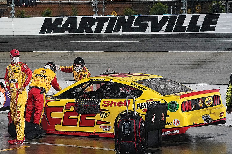 Joey Logano looks over pit row as his crew covers his car during a rain delay Saturday night in the NASCAR Cup Series race at Martinsville Speedway in Martinsville, Va.