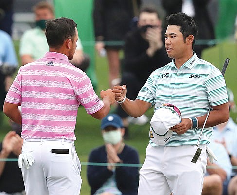 Hideki Matsuyama (right) and Xander Schauffele give each other a fist-bump on the 18th green as they finish Saturday's third round of the Masters at Augusta National in Augusta, Ga.