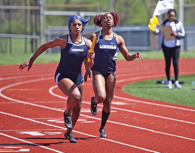 Lincoln's Rene Medley (left) takes the baton on a handoff from Vivian Akunna during the women's 4x100-meter relay Sunday in the Lincoln Open at Dwight T. Reed Stadium.