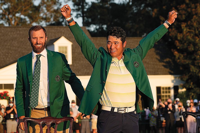 Hideki Matsuyama raises his arms after putting on champion's green jacket after winning the Masters as Dustin Johnson watches Sunday in Augusta, Ga.