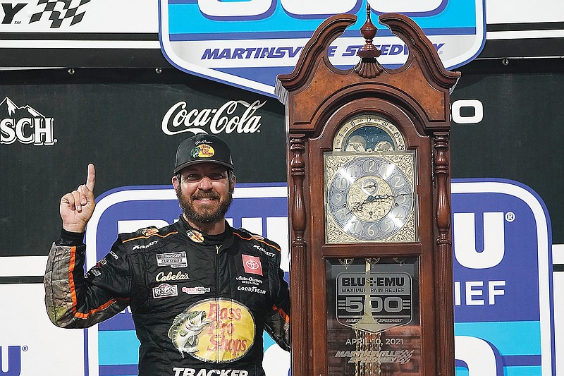 Martin Truex Jr. celebrates with the winners trophy Sunday after winning the NASCAR Cup Series race at Martinsville Speedway in Martinsville, Va.