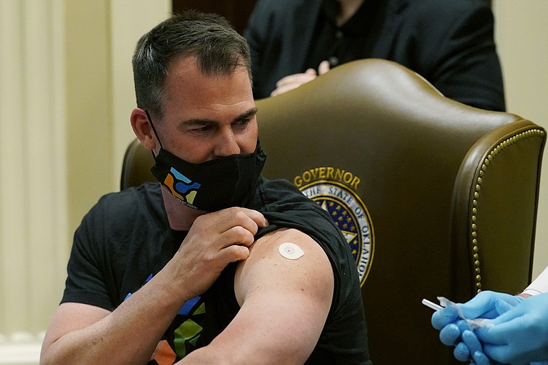 FILE- In this March 29, 2021 file photo, Oklahoman Gov. Kevin Stitt looks back at the needle after looking away while being administered the Johnson & Johnson vaccine following a news conference about opening vaccine eligibility, in Oklahoma City. Oklahoma health officials are halting distribution of the single-dose Johnson & Johnson vaccine. (AP Photo/Sue Ogrocki, File)