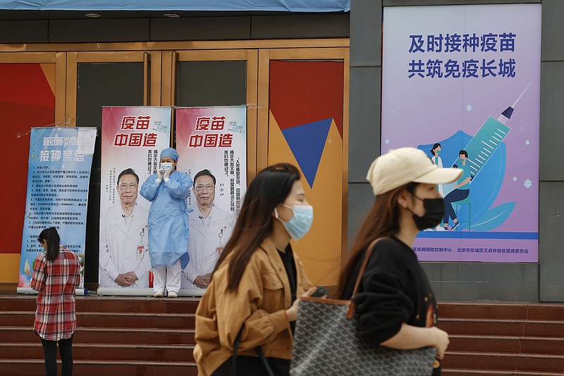 A medical worker stands near billboards portraying renowned Chinese Dr. Zhong Nanshan with the words "Vaccine China Made" at a vaccination site in Beijing on Friday, April 9, 2021. China's success at controlling the coronavirus outbreak has resulted in a population that has seemed almost reluctant to get vaccinated. Now, it is accelerating its inoculation campaign by offering incentives — free eggs, store coupons and discounts on groceries and merchandise — to those getting a shot. ​(AP Photo/Ng Han Guan)
